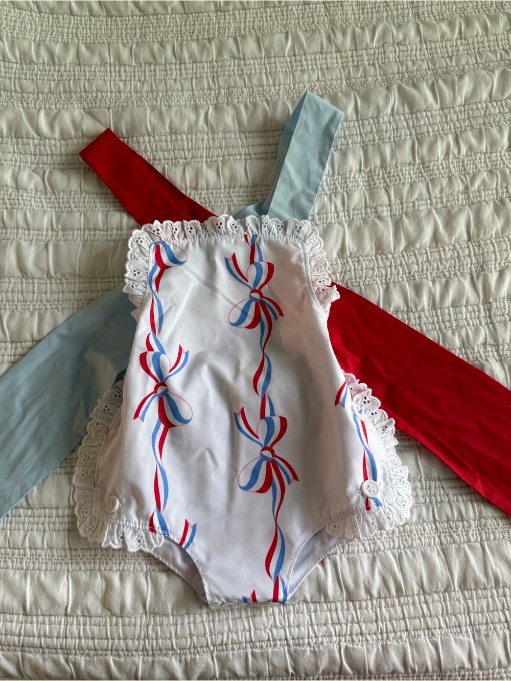 The Beaufort Bonnet Company White Baby One-Piece with Red and Blue Ribbon Detail